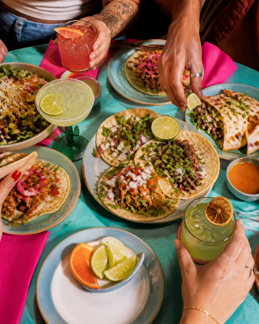Friends sharing Mexican food and colorful drinks around a table